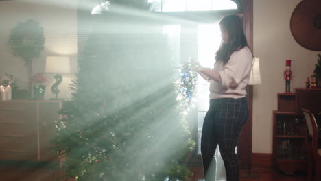 woman decorating a christmas tree with lights