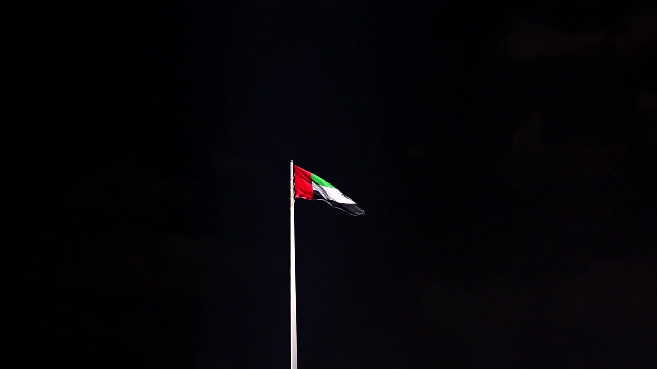 The UAE flag flying gracefully at night.