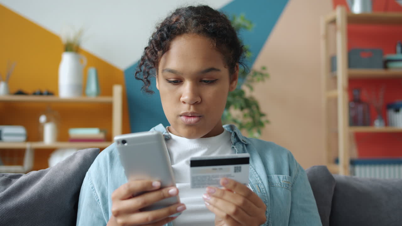 Teenager using mobile phone and credit card for online shopping
