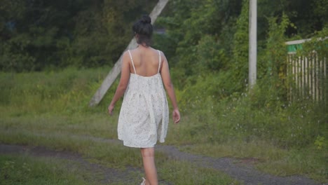 Dama-Atractiva-Caminando-Con-Un-Vestido-Blanco-En-La-Naturaleza-Suburbana,-Filmada-En-Cámara-Lenta-Con-Una-Actitud-De-Nueva-Generación