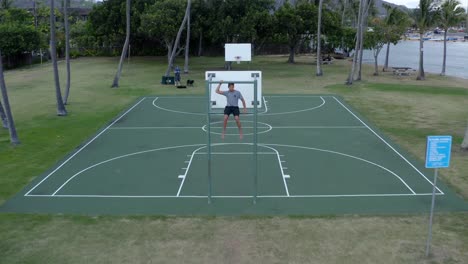 Niño-Se-Sienta-En-El-Tablero-De-Baloncesto-En-La-Cancha-Tropical-En-Hawaii