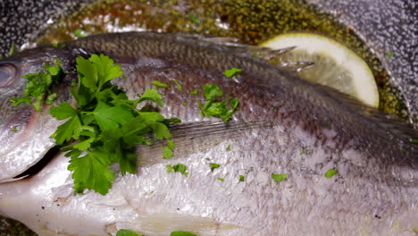 pouring parsley on bream fish while cooking in a pan