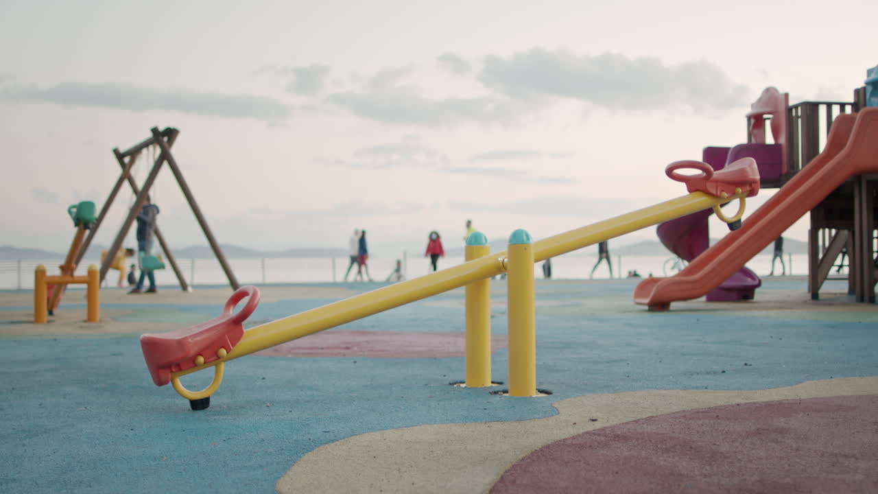 el colorido patio de recreo está vacío en tiempos de cuarentena de coronavirus mientras un niño se balancea en el fondo en cámara lenta