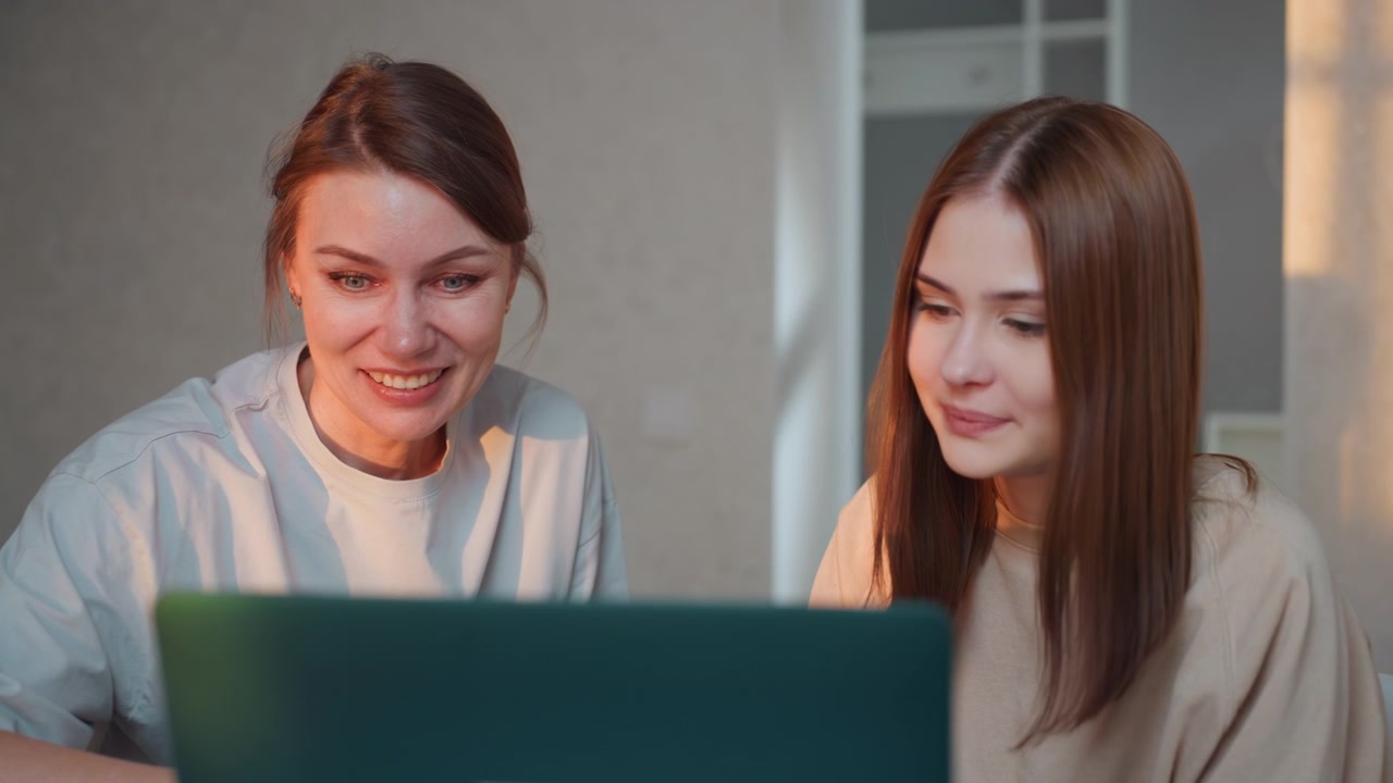 Due donne caucasiche al laptop, tutor e studentessa che praticano grammatica e compiti in un ambiente domestico accogliente, luce serale soffusa, coach paziente spiega i concetti, atmosfera calda e di supporto, attenzione sullo schermo