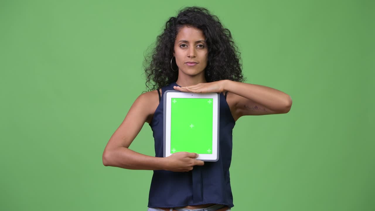 Ung, smuk latinamerikansk forretningskvinde viser digital tablet.