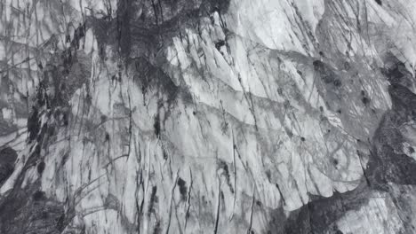 aerial view above a ashy, darkened glacier surface, in iceland - birds eye, drone shot