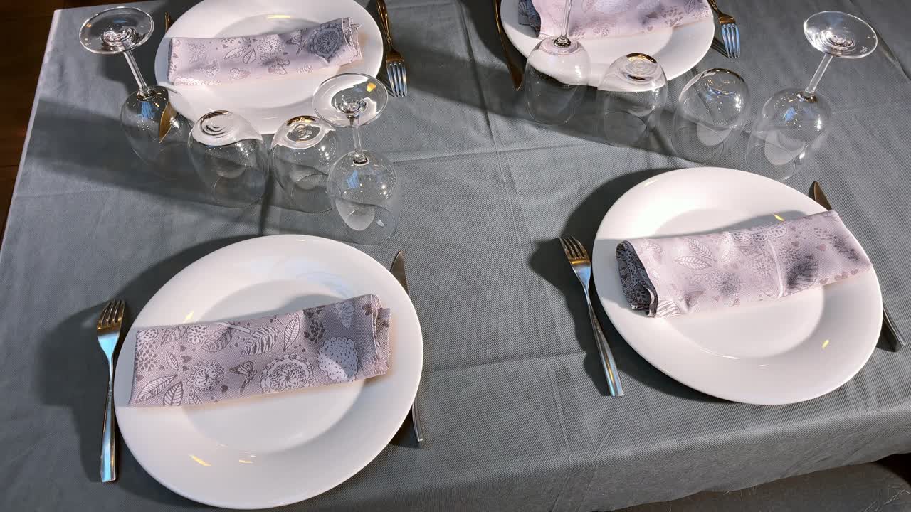 servilletas de tela morada en una mesa bien vestida con platos, vasos y cubiertos
