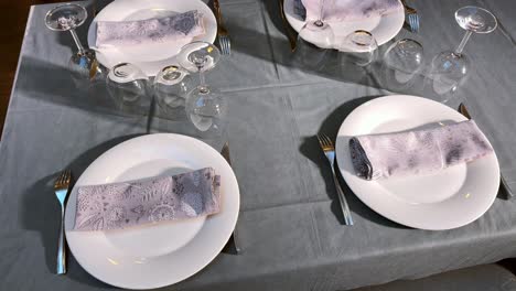 purple cloth napkins at well-dressed table with plates, vessel and cutlery