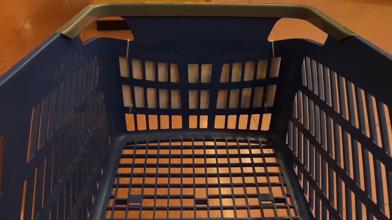 POV-bild av en tom blå plastkundkorg som bärs genom en stormarknad. Idealisk för detaljhandel, konsumtion och livsmedelskoncept.