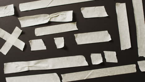 video de un primer plano de varias piezas de cinta de papel blanco sobre un fondo negro