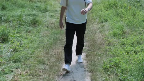 young man walking with guitar on street near forest