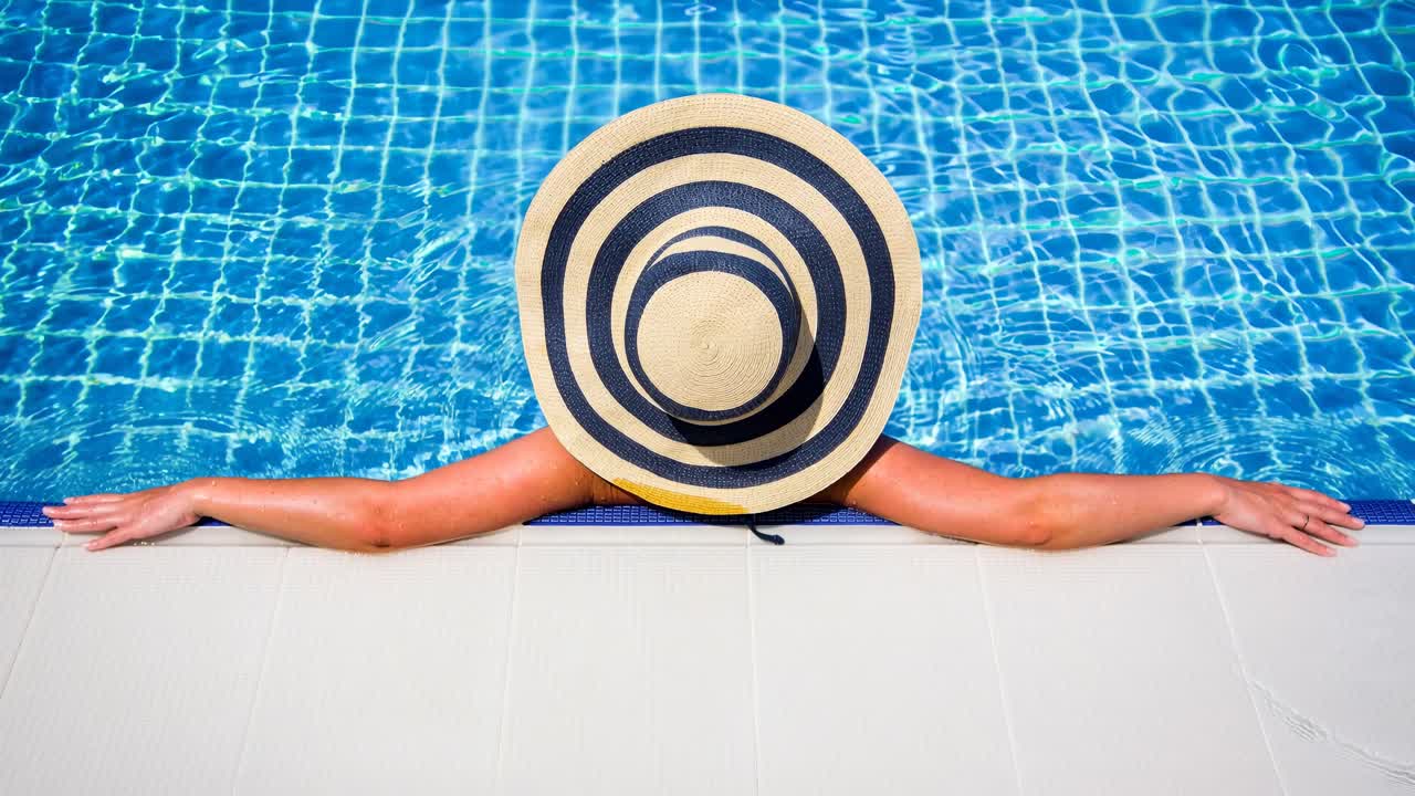 Woman in straw hat relaxing swimming pool