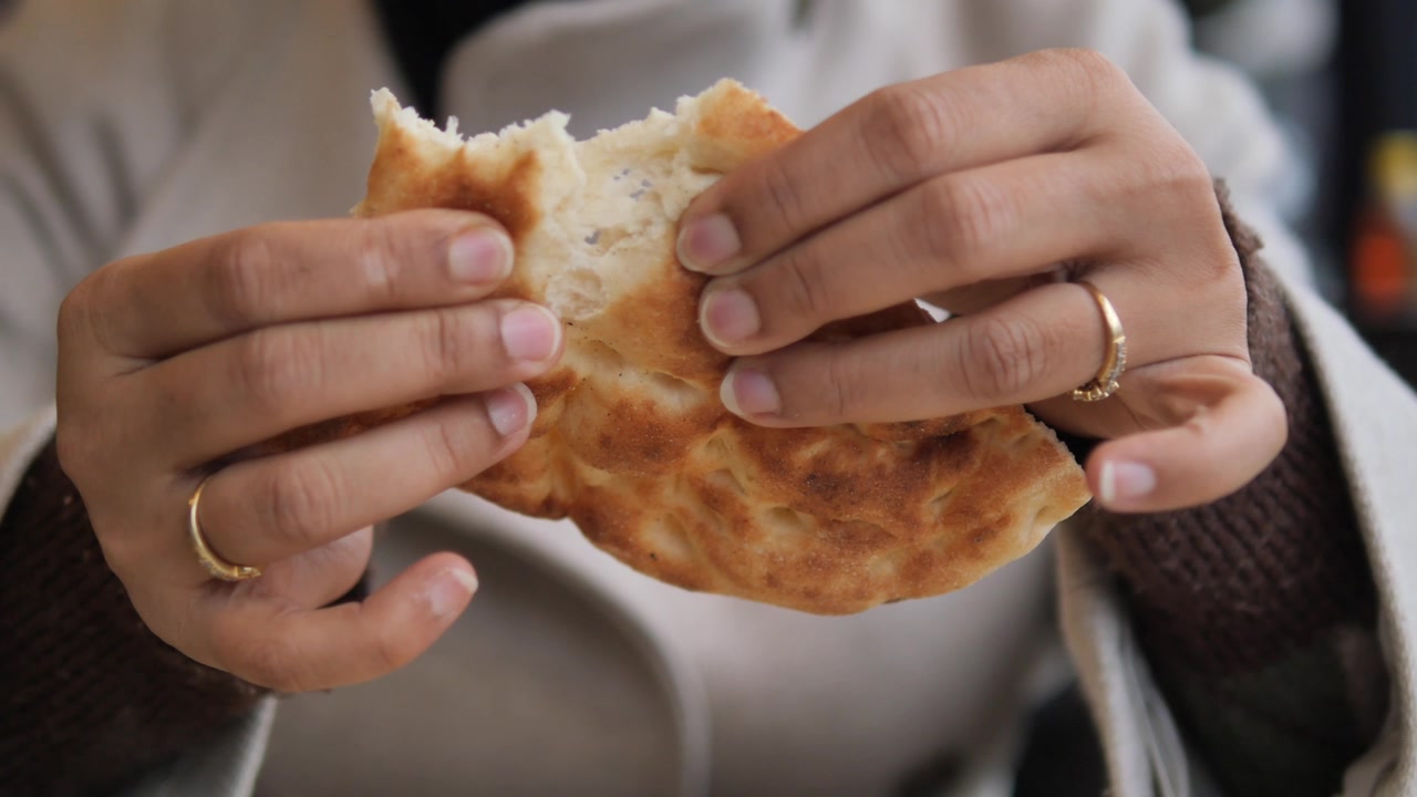 Person Tearing Fresh Flatbread in Half
