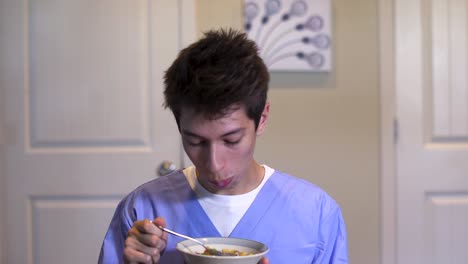 Man-wearing-scrubs-takes-bite-of-cereal