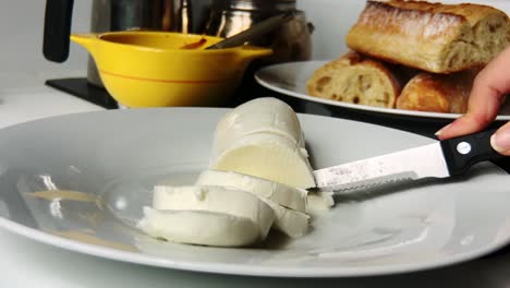 persona cortando queso mozzarella fresco con un cuchillo