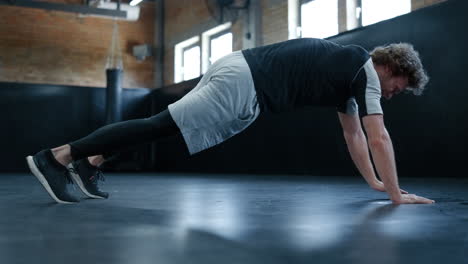 young fighter making exercises in sport club. sportsman doing push ups at gym