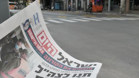 israel newspaper with corona virus info and empty tel aviv street in background