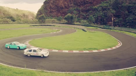 Two-high-performance-cars-drifting-or-sliding-around-hairpin-turn-of-race-track