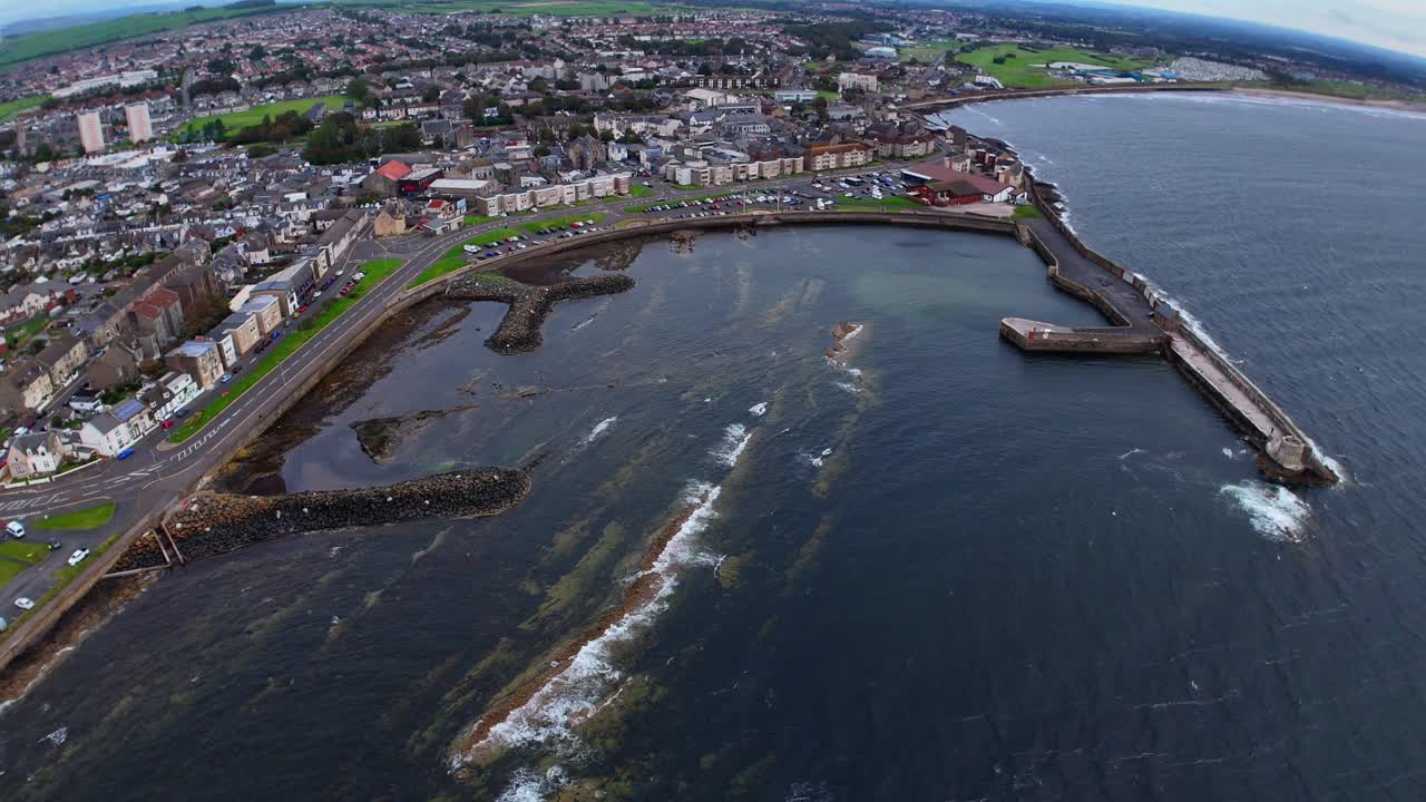 Aerial View, Saltcoats waterfront in Scotland, showing local businesses, passing traffic, the stone pier and the coastal town backdrop by the sea