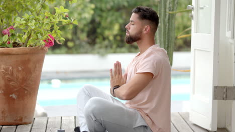 meditating outdoors, man sitting cross-legged with hands in prayer position