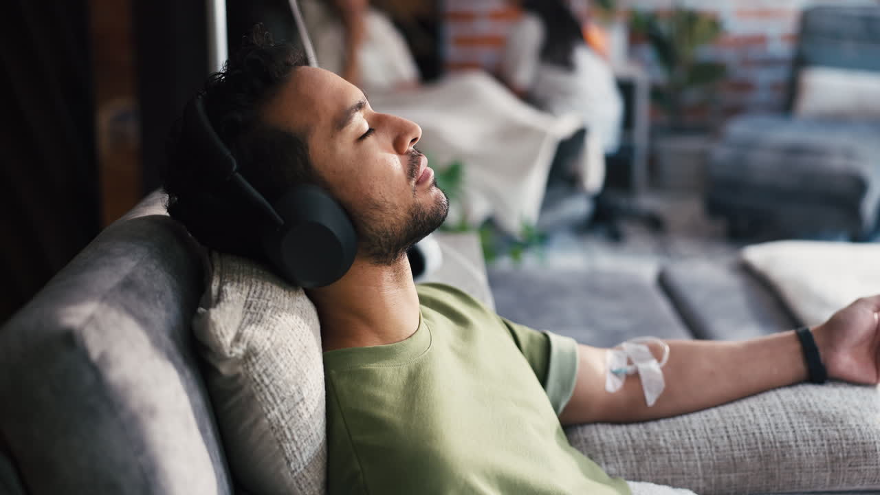Man with Headphones Resting on Couch During IV Drip Treatment