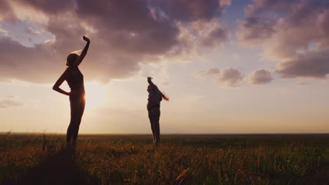 silhouette of a young woman with a child doing fitness in nature