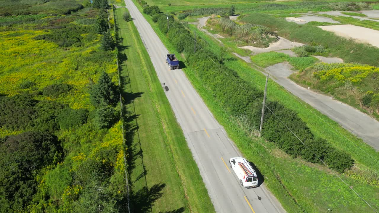 Veduta aerea di auto e camion che percorrono una strada rurale dritta attraverso la campagna