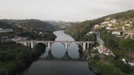 dolly out shot of antique historical bridge with arches crossing tamega river at entre os rios portugal