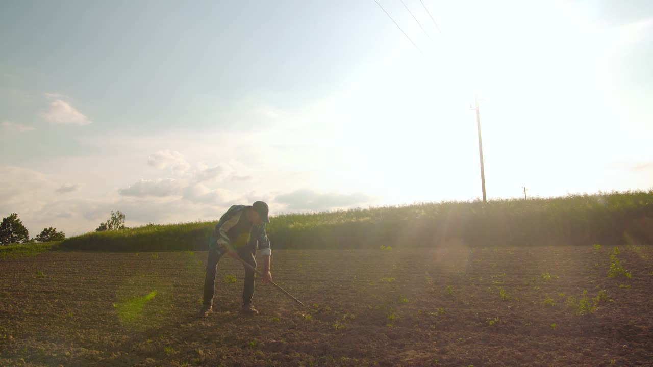 화난 농부가 농장에서 들판에 괭이를 던지고 있다