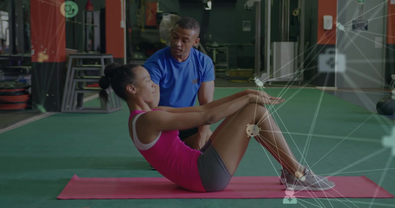 Trainer counting cues, tapping hip as client performing crunches on red gym mat for alignment