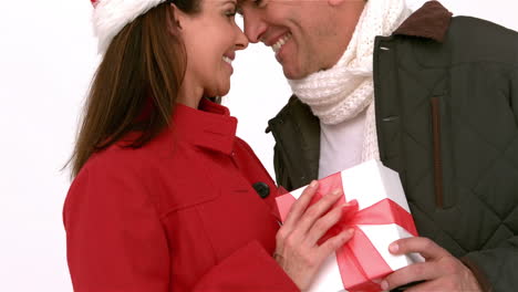 una pareja feliz de nariz a nariz sosteniendo un regalo de navidad.