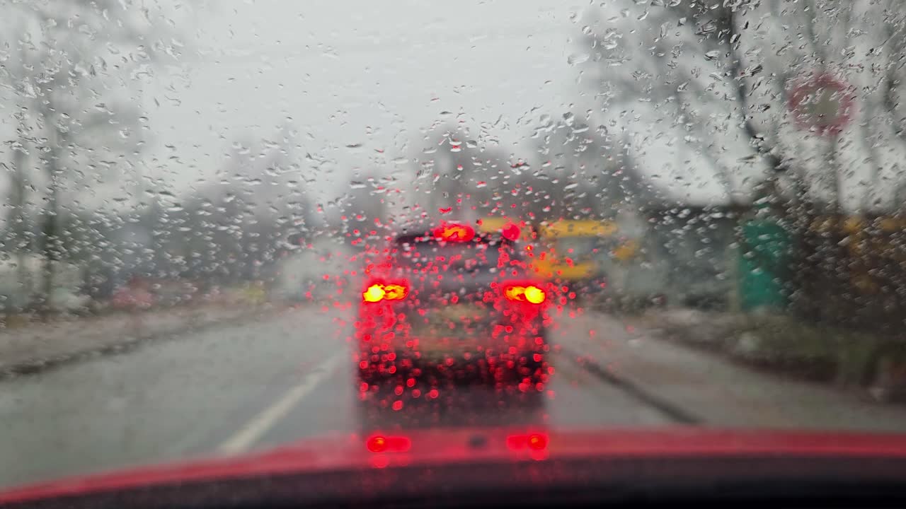 Urban traffic jam in rain with train crossing in background, focus on droplets