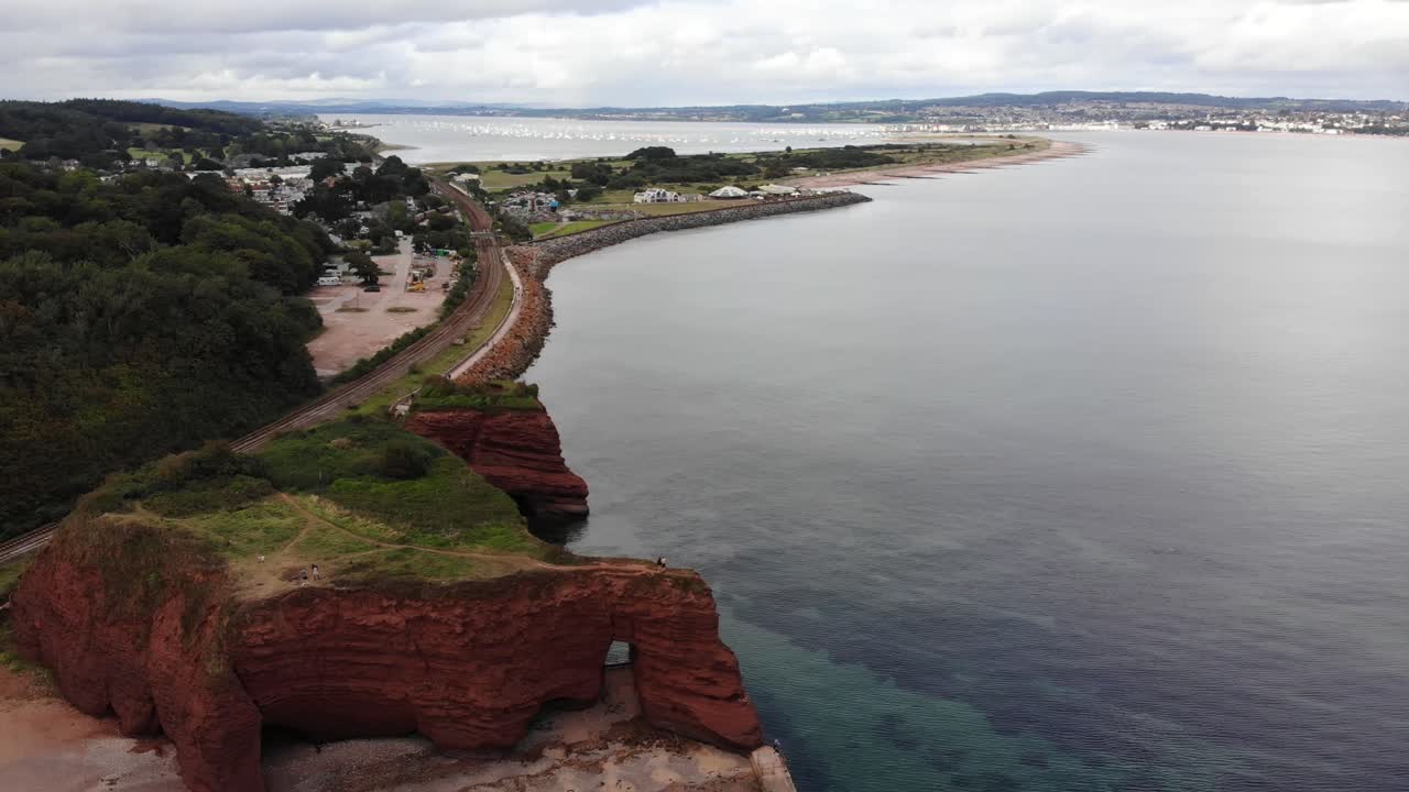 Aerial perspective of Dawlish's coastline featuring prominent red sandstone formations. Pull Back Shot