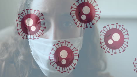 multiple covid-19 cells moving against portrait of caucasian woman wearing face mask