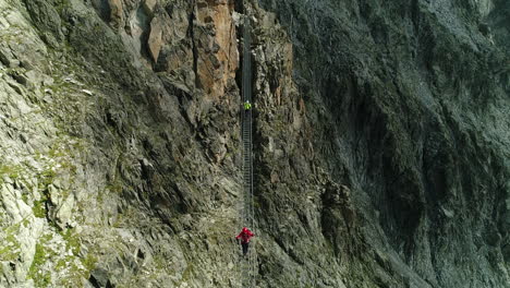 aerial drone view of professional trekker walking on high altitude hanging bride in alps