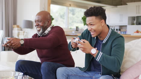 Emocionado-Padre-Afroamericano-E-Hijo-Adulto-Jugando-Videojuegos-Con-Gamepads-En-Casa,-Cámara-Lenta