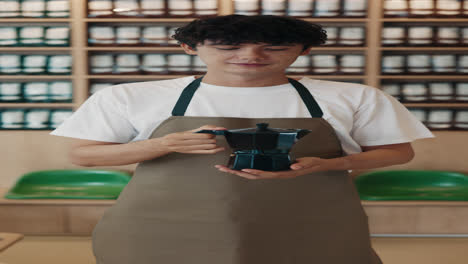 man holding a moka pot in a coffee shop