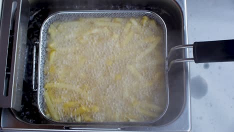 Top-view-of-french-fries-deep-frying-in-wire-basket