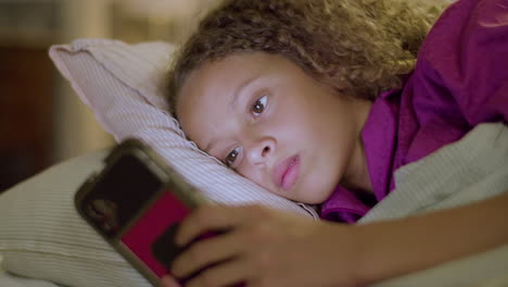 primer plano de una linda chica acostada en la cama, deslizando la pantalla del teléfono inteligente