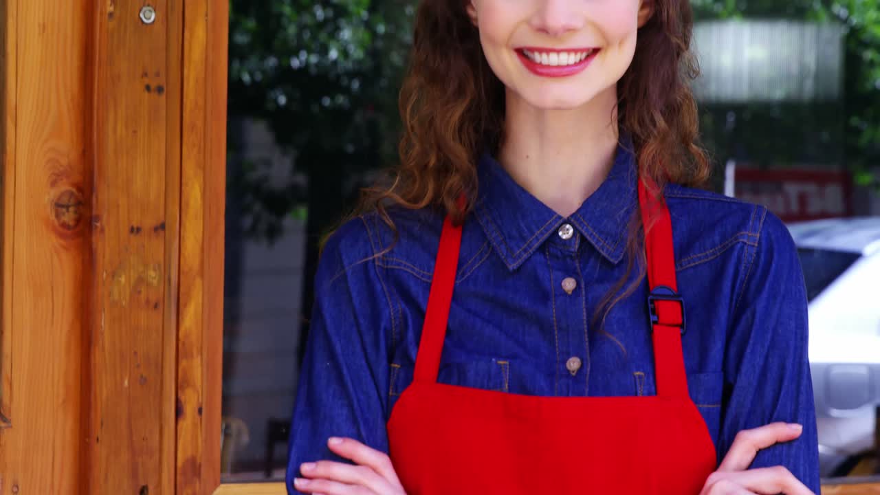 Smiling waitress standing at the entrance of caf&Atilde;&copy;