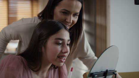 caucasian woman teaching daughter how to do make up for a prom