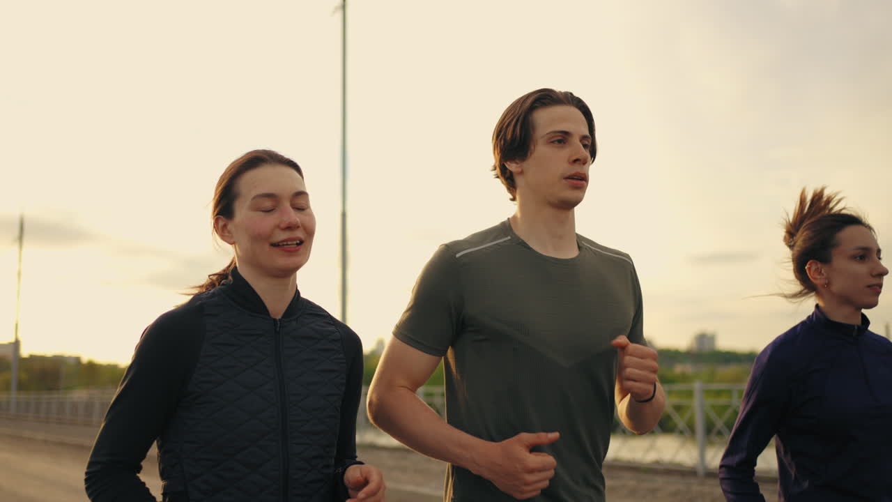 세 명의 젊은 운동 선수 들 이 아침 이나 저녁 에 함께 조 ⁇  하고 있으며, 프로 달리기 선수 들 의 야외 훈련 을 하고 있다