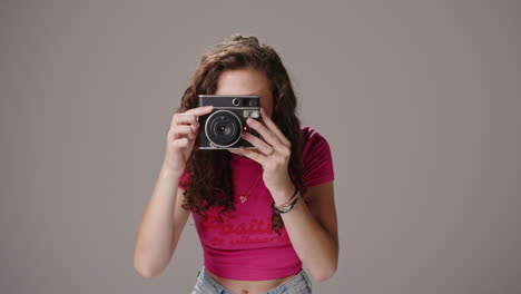 caucasian brunette brings instant film camera up to face to take picture