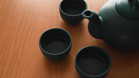 minimal background of a green japanese tea set with steam coming out of the cups, on a wooden table