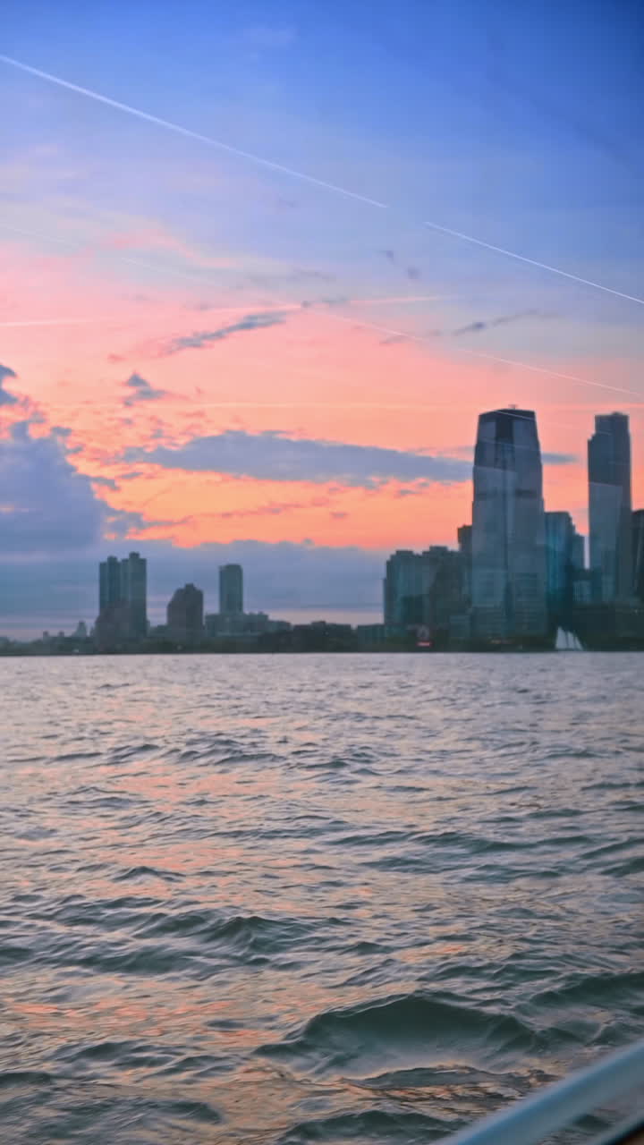 Passeio de barco pelo rio turbulento ao pôr do sol. Skyline de Nova York no cenário de céu rosa. Vídeo vertical
