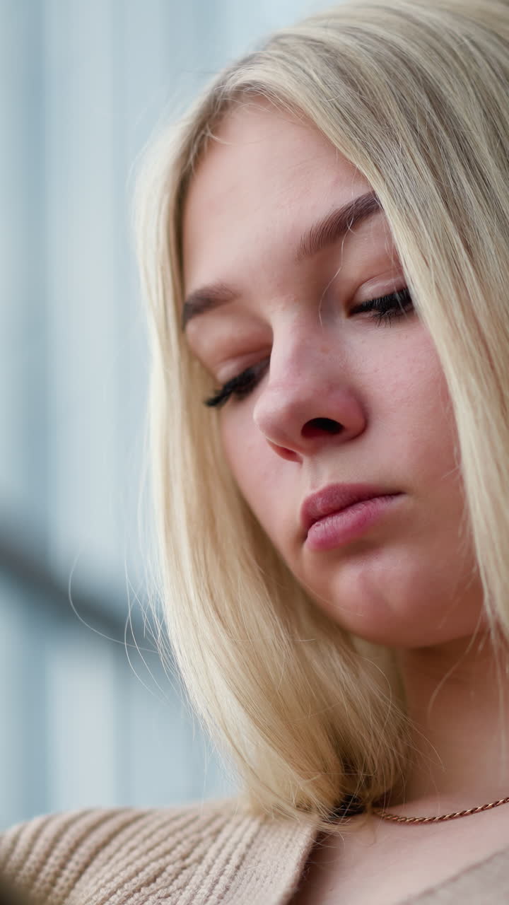 Focused young woman with blonde hair reading her book in a relaxed setting, lost in thought with a slight blur in the background, showing a sense of calm and concentration