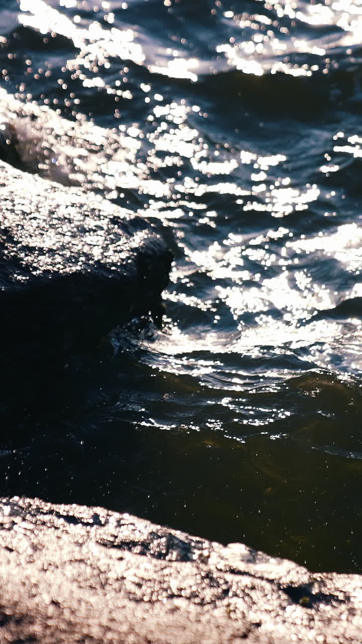 Close up of sea splash by coast. Crashing ocean waves on rocks. Vertical video