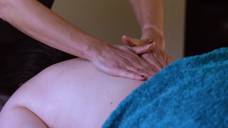 unrecognisable woman gets professional upper back massage in spa salon in slow motion.