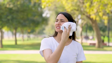 mujer india limpiando el sudor después de una sesión de carrera en un parque por la mañana