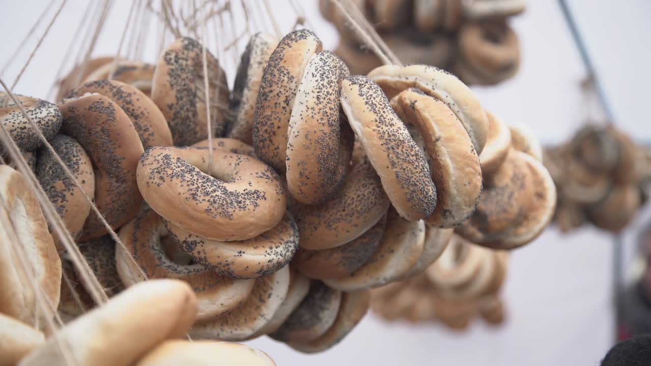 подвесные кольцеобразные рулоны в тарелке для продажи на белом фоне, булочки, хлебные кольца с маковыми семенами